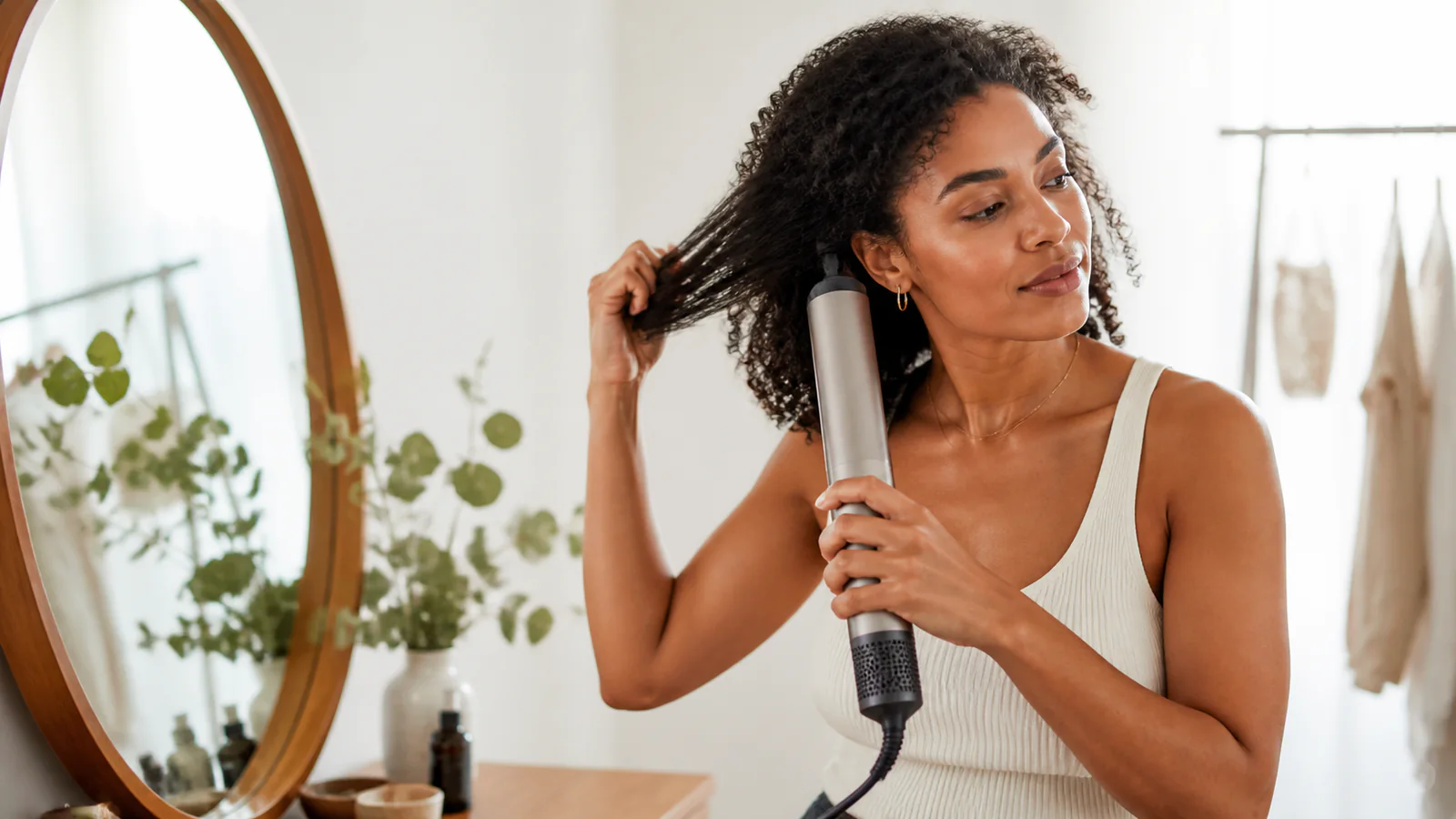 Woman with textured hair using an unbranded air-drying wand in a bright dressing area